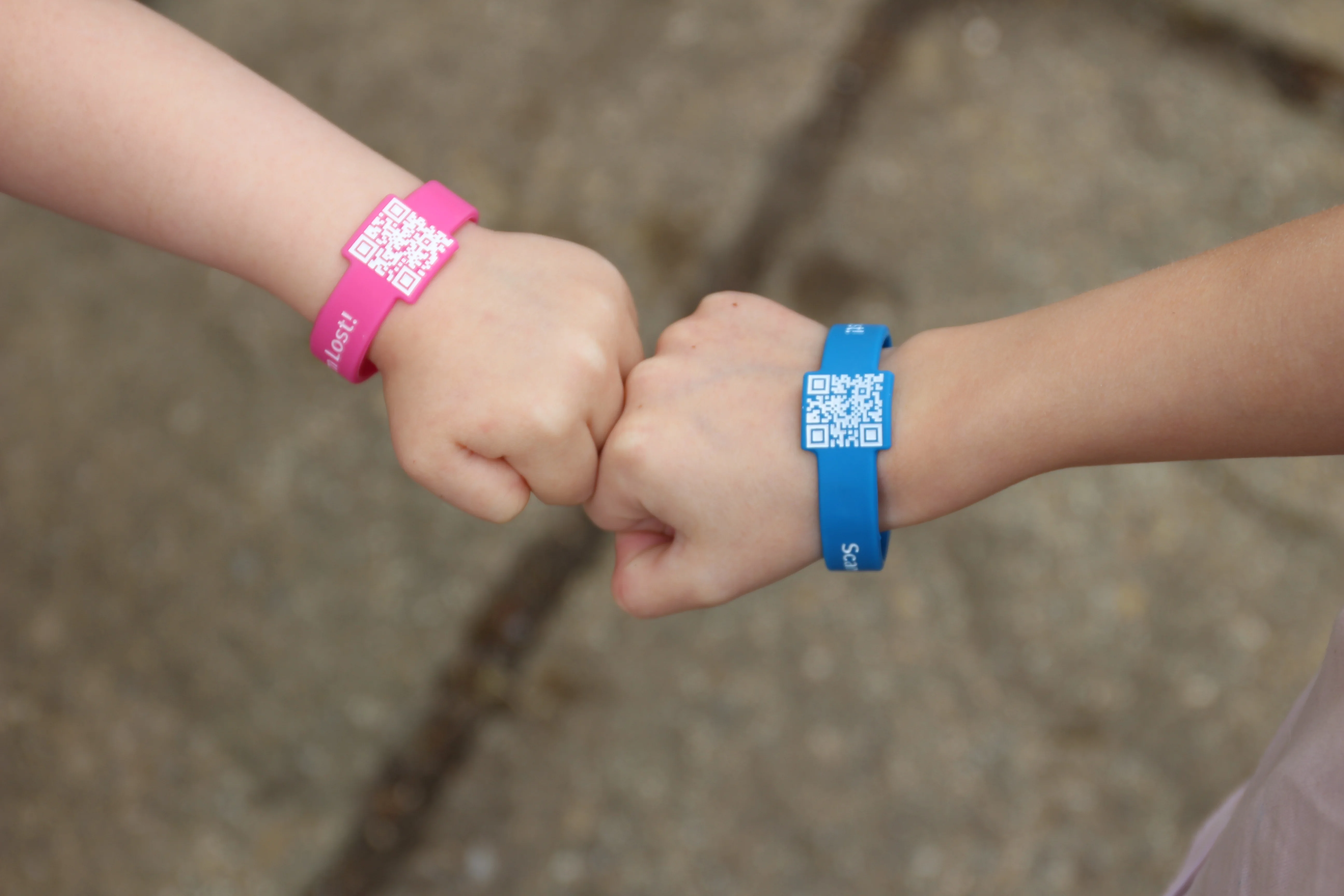 A child's wrist wearing an orange QR-code wristband at a theme park